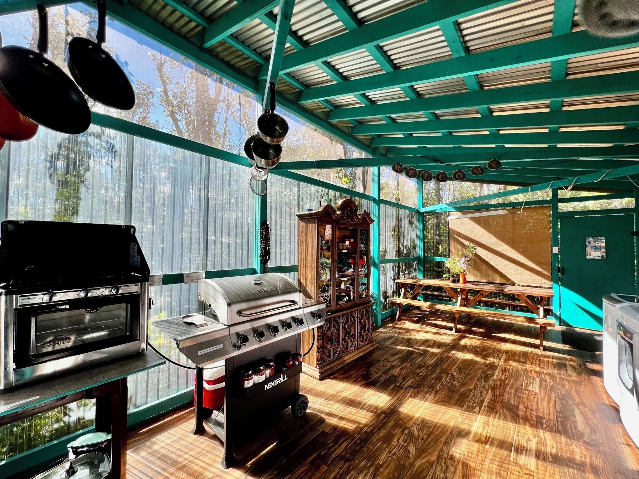 An outdoor kitchen area with a gas stove, grill, and hanging pots.