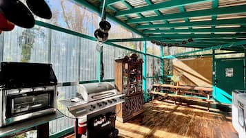 An outdoor kitchen area with a gas stove, grill, and hanging pots.