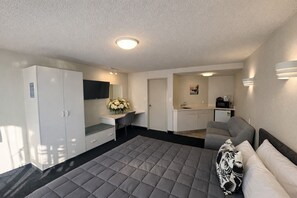 A compact hotel room with a bed, a desk, a kitchenette, and a wardrobe. - BK's Fountain Court Motel (Napier)