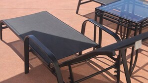 A poolside area with a lounge chair, a table, and a potted plant. - BK's Fountain Court Motel (Napier)