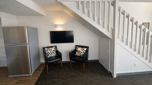 A modern living room with a staircase, a flat-screen TV, and a refrigerator. - BK's Fountain Court Motel (Napier)