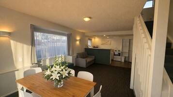 A compact living space with a dining area, kitchenette, and a staircase.