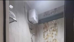 A bathroom with a shower, toilet, and towel. - Phoenix Living (Surabaya)