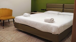 A modern hotel room with a bed, a chair, and a nightstand. - The Cloud Hotel (Puducherry)