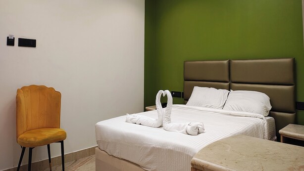 A hotel room with a bed, a chair, a nightstand, and a marble table. - The Cloud Hotel (Puducherry)
