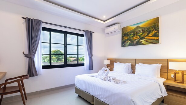 A hotel room with a large bed, a desk, and a window with curtains.