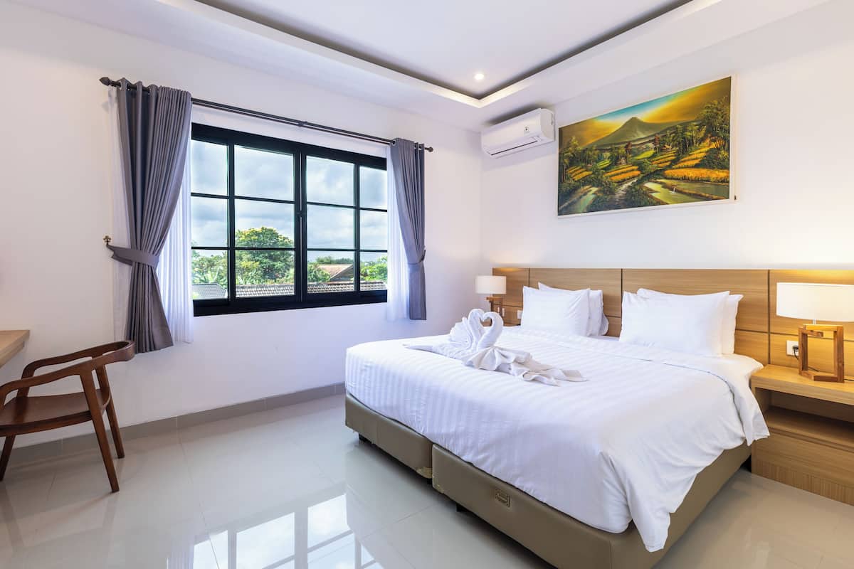 Una habitación de hotel con una cama grande, un escritorio y una ventana con cortinas.