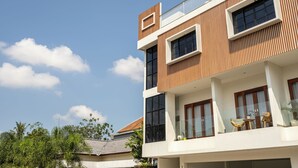A modern multi-story building with a balcony, large windows, and a clear sky.