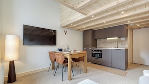 A modern kitchen with a built-in oven and a dining area with a wooden table and chairs.