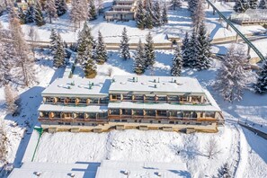 A multi-story hotel with a flat roof, surrounded by snow-covered trees and a ski lift in the background. - Studio Sansi 34 with Balcony Views, Cesana Torinese, Italy (Cesana Torinese)