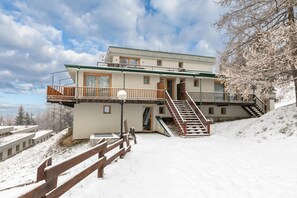 A multi-story building with a balcony, a staircase, and a snow-covered landscape. - Studio Sansi 34 with Balcony Views, Cesana Torinese, Italy (Cesana Torinese)
