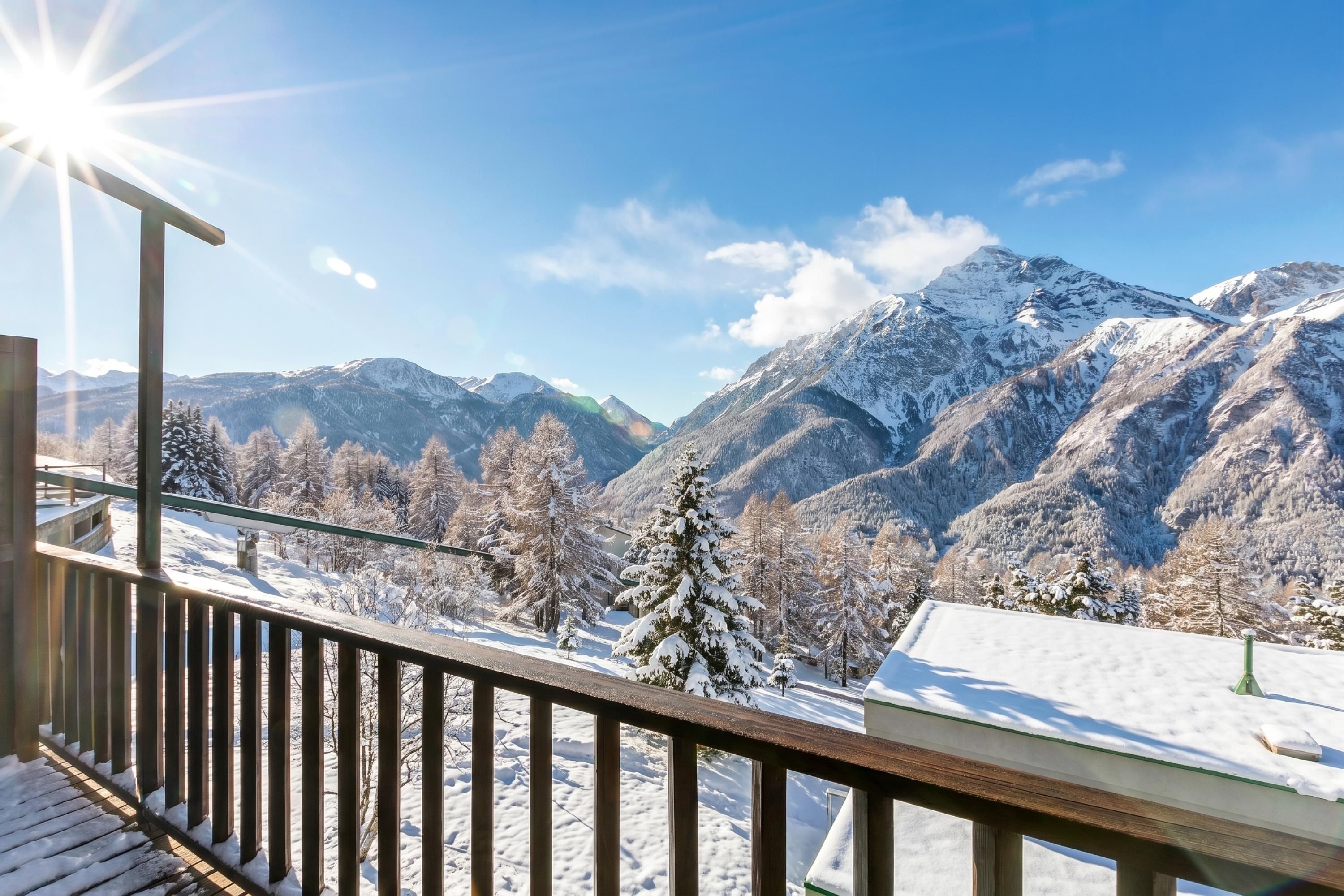 Eine Holzterrasse mit Blick auf schneebedeckte Berge und einem klaren Himmel.