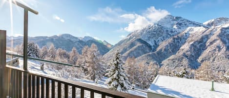 A wooden deck with a view of snow-covered mountains and a clear sky.