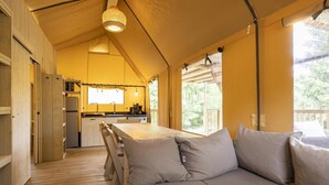 A cozy cabin with a wooden deck, a dining area with a bench, and a kitchen with a window.