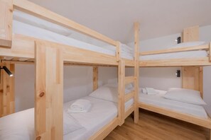 A bunk bed room with wooden frames, white bedding, and a wooden wardrobe. - Résidence Grand Roc - Campanules 424, Argentière (Chamonix), France (Argentière (Chamonix))