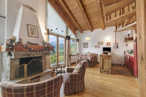 Un interior acogedor con chimenea, vigas de madera, comedor y cocina.