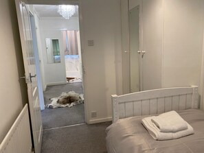 A bedroom with a bed, a radiator, a door leading to another room, and a fur rug on the floor. - London Charm - 3 Bedroom House Near Canary Wharf (London)