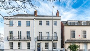 A multi-story building with a white facade, multiple windows, and a balcony with a wrought iron railing. - Clarendon Place - Stunning 1BD in Leamington Spa (Royal Leamington Spa)
