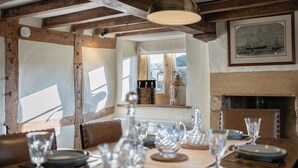 Zona pranzo con tavolo in legno apparecchiato per un pasto, camino e finestra con vista.