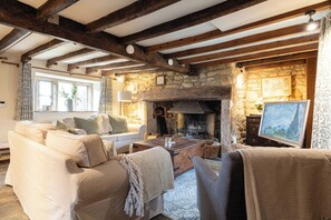 A cozy living room with a stone fireplace, wooden beams, a white sofa, and a painting on the wall. - Orchard Cottage, Lovely Home near Broadway (Broadway)