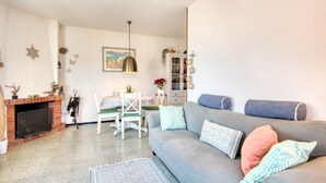 A living room with a fireplace, a sofa, a dining table, and chairs. - ROSA DELS VENTS: Very central apartment in l'Escala (L'Escala)