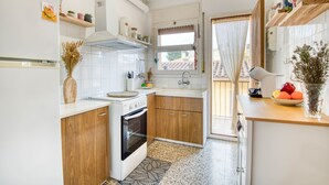 A modern kitchen with white cabinets, wooden accents, a built-in oven, and a window with a view. - ROSA DELS VENTS: Very central apartment in l'Escala (L'Escala)