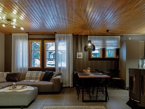 A cozy living room with a sofa, a dining table, and a kitchen area with a refrigerator.