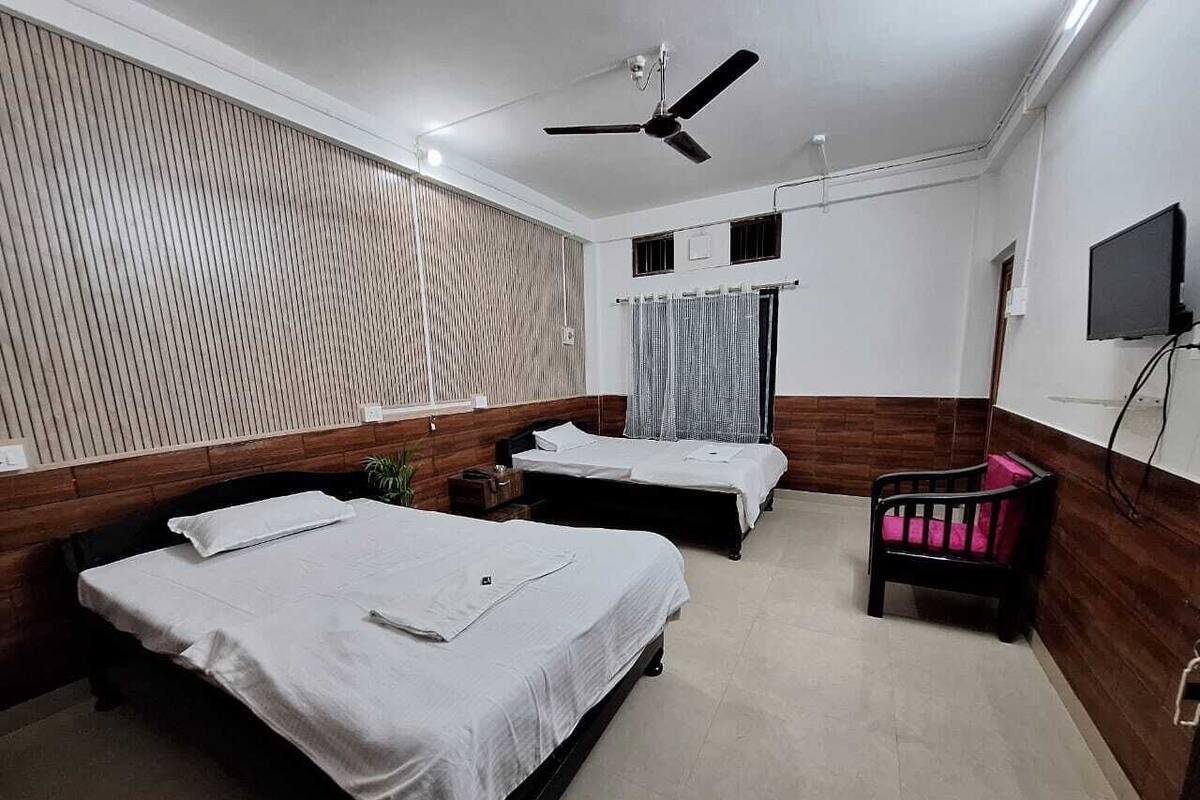 Ein Hotelzimmer mit zwei Betten, einem Deckenventilator, einem Fernseher und einer Holzwand.