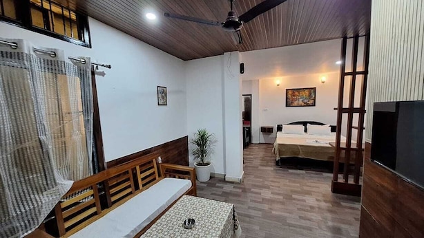 A room with a wooden ceiling, a ceiling fan, a bed, a table, and a TV. - Hotel High East (Papumpare)