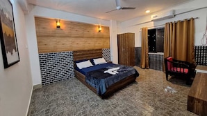 A hotel room with a bed, a ceiling fan, a wooden headboard, a black and white tiled wall, a wooden door, and a window with curtains. - Hotel High East (Papumpare)