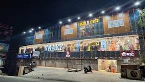 A V-MART store at night with a large sign, a scooter parked in front, and a building with a wooden facade. - Hotel High East (Papumpare)