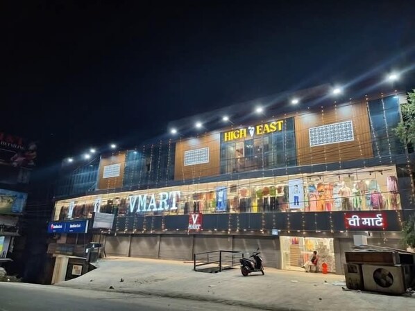 A V-MART store at night with a large sign, a scooter parked in front, and a building with a wooden facade. - Hotel High East (Papumpare)