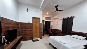 A hotel room with a bed, a TV, a ceiling fan, and a wooden accent wall. - Hotel High East (Papumpare)