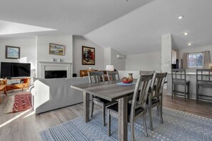 A modern living space with a dining area, kitchen, and entertainment setup. - Bethel Inn Townhouse 524 (Bethel)