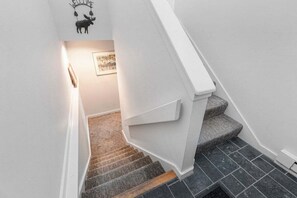 A staircase with a white handrail, grey carpeted steps, and a dark tiled floor. - Bethel Inn Townhouse 524 (Bethel)