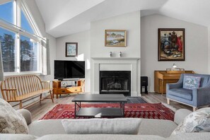 A living room with a fireplace, television, and a piano. - Bethel Inn Townhouse 524 (Bethel)