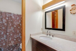 A bathroom with a sink, mirror, and shower curtain.