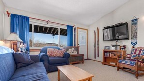 A living room with a sofa, armchair, coffee table, TV, and a bookshelf.