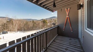 A wooden deck with a view of a snowy landscape and mountains.