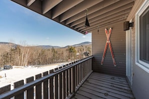 A wooden deck with a view of a snowy landscape and mountains.