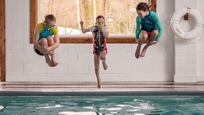 Tres personas saltan a una piscina desde un trampolín.