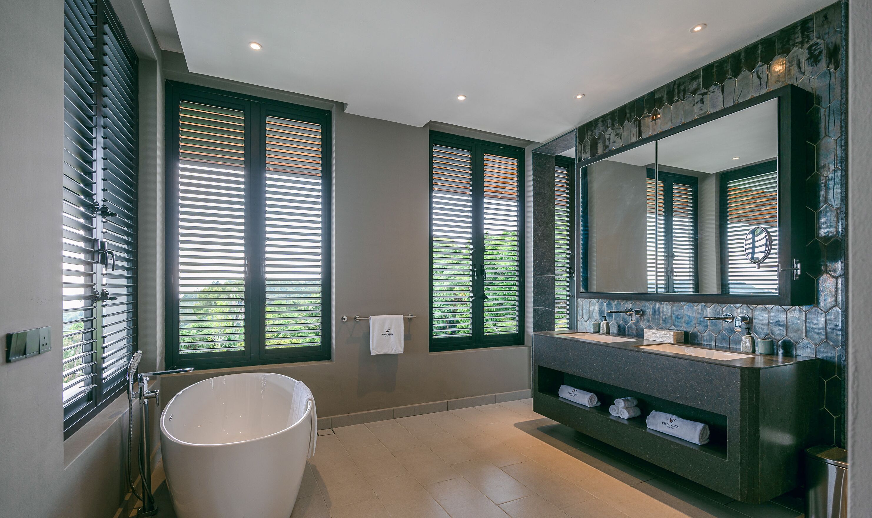 A modern bathroom with a freestanding bathtub, a large mirror, and a vanity with a sink and towel storage.