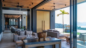 A modern living room with a large window, a wooden ceiling, and a view of the mountains.