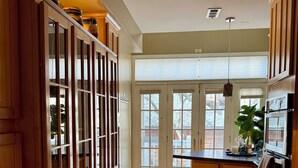 A kitchen with wooden cabinets, a central island, and a large window. - Ideal Group Getaway: Prime Location, Parking, Backyard, Sunroom & Pet-Friendly (Chicago)