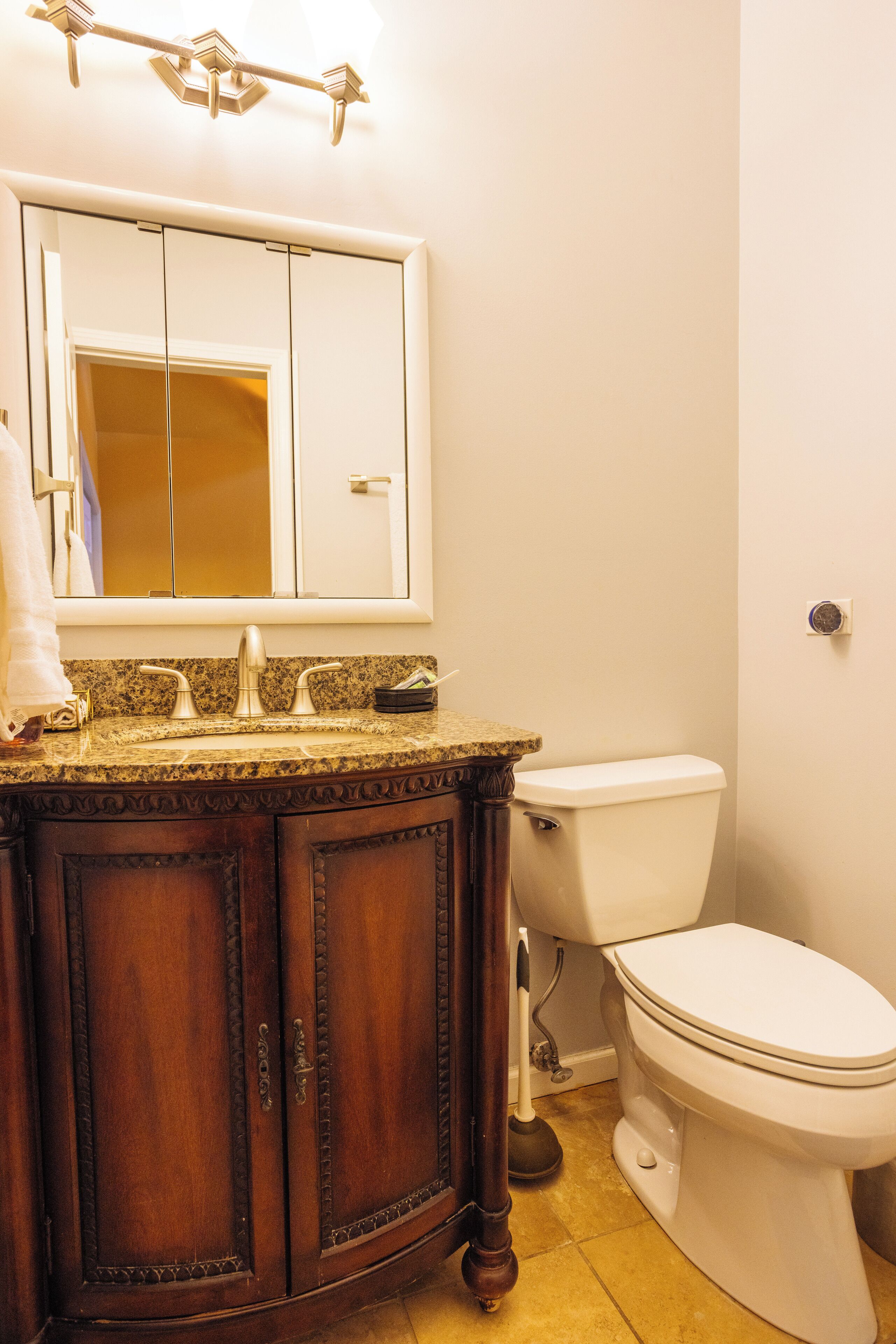 A bathroom with a wooden vanity, a sink, a toilet, and a mirror.