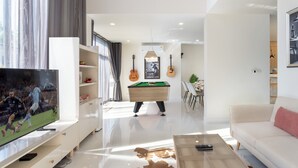 Un salon moderne équipé d’un téléviseur à écran plat, d’une table de billard et d’un canapé.