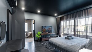 Une chambre moderne avec un grand lit, un bureau, une télévision et une vue sur l’extérieur.