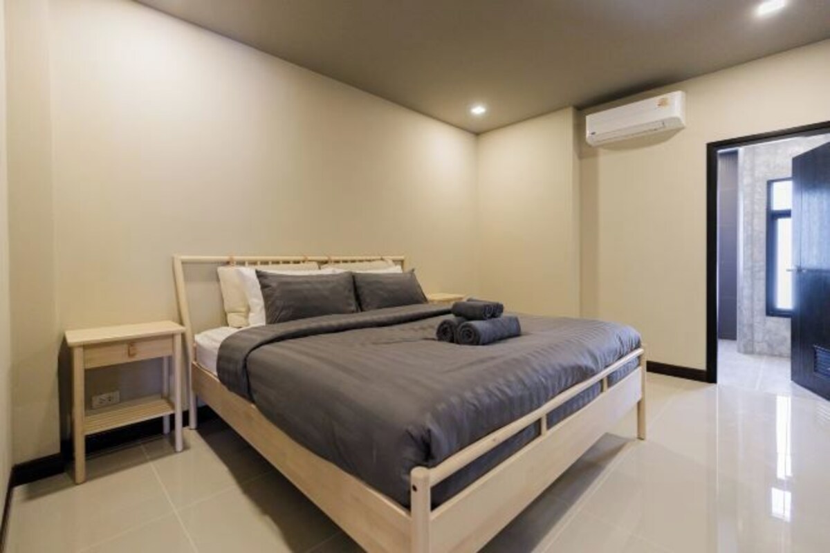 A bedroom with a bed, bedside table, and an air conditioning unit.