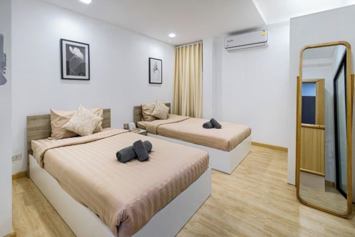 A hotel room with two beds, a large mirror, and an air conditioning unit on the wall.
