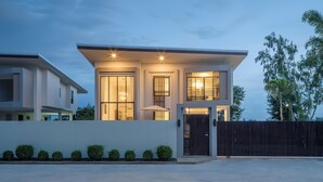 Une maison moderne à deux étages, dotée d’un toit plat, de grandes fenêtres et d’une clôture sombre.